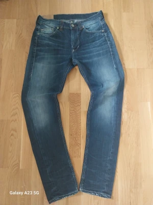 Dondup jeans - Säljer ett par blå jeans från dondup med snyggt tvättad effekt och klassisk femficksmodell. Jeansen har raka ben och kontrastsömmar som ger en stilren vibe. Perfekta för dig som gillar en avslappnad men ändå trendig stil.