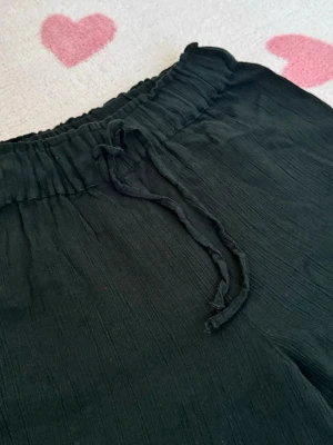 Svarta vida linnebyxor med dragsko - Säljer ett par svarta linnebyxor med avslappnad passform och breda ben. Byxorna har resår i midjan och justerbar dragsko för extra komfort. Perfekta för en chill och stilren look. Materialet är luftigt och lätt, vilket gör dem sköna att bära under varma dagar☀️💗