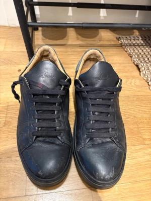 Svarta sneakers från Van Laack - Snygga svarta sneakers från Van Laack i läder med svarta skosnören och beige innersida. Skorna har en klassisk låg profil och diskret logga på både plös och häl. Perfekta för dig som gillar stilrena och tidlösa sneakers.