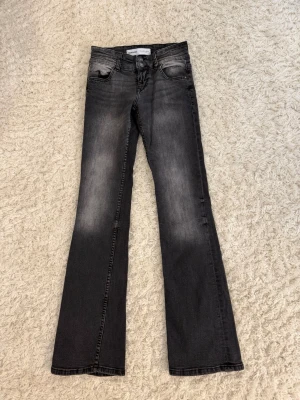 Svarta bootcut jeans från Bershka  - Säljer ett par svarta bootcut jeans från Bershka med snygg tvättad look och slitningar vid fickorna. Jeansen har klassisk femficksmodell och lågmmidja. Perfekta för dig som gillar en avslappnad men trendig stil. 
