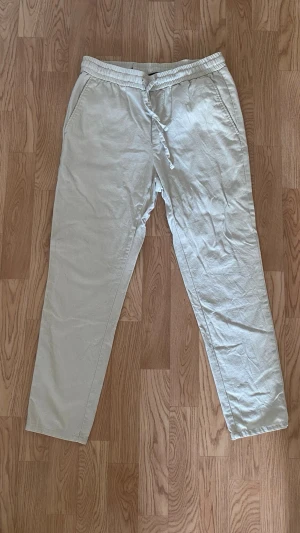 Beiga linnebyxor Only & Sons - Snygga beiga linnebyxor från Only & Sons med avslappnad passform och dragsko i midjan. Tillverkade i ett luftigt linnematerial som passar perfekt för varma dagar. Klassisk rak modell med elastisk midja för extra komfort.