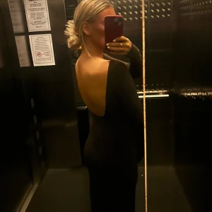 Mörbrun långklänning med öppen rygg - Snygg mörkbrun långklänning med lång ärm och en djup öppen rygg. Klänningen har en figurnära passform endast en gång använd! Så har inga defekter 