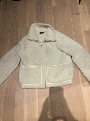 Vit teddyjacka trendig - Mysig vit teddyjacka från lager med dragkedja framtill och två stora fickor. Jackan har hög krage och är gjord i fluffigt teddy-material som håller dig varm. Perfekt för kalla dagar och enkel att matcha med olika outfits. Trendig skriv för frågor💗kan gå ner i pris vid snabb affär❤️
