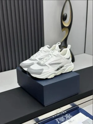Diors b22 vita sneakers med grå detaljer - Stilrena chunky sneakers i vitt med grå detaljer och meshpaneler. Skorna har tjock sula och sportig design, perfekta för en trendig streetstyle-look. Ovandelen kombinerar mesh och syntetmaterial för extra komfort och andningsförmåga.