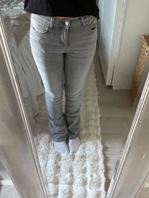 Grå bootcut jeans low waist - Snygga grå bootcut jeans med klassisk femficksdesign och normal midja. Jeansen har en lätt utsvängd passform nertill och stängs med dragkedja och knapp. Perfekta för dig som gillar en stilren och enkel look.
