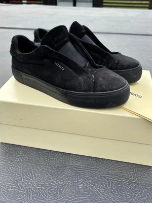 Svarta sneakers från Axel Arigato - Stilrena svarta sneakers från Axel Arigato i mocka. Skorna är köpt för 2700 kr och är inprincip nya! Kartong och skopåse medföljer! (Passar även 42)
