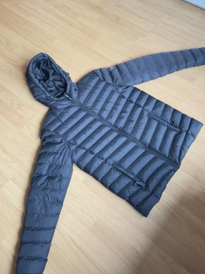 Vinson svart dunjacka/vinterjacka med huva – Strl S - Snygg och varm svart Vinson jacka med huva säljes. Perfekt som höst- och vinterjacka. Jackan är lätt, bekväm och har en stilren passform med dragkedjefickor på sidorna.  Storlek: S Märke: Vinson Färg: Svart Skick: Bra skick  Modellen på bilden är ca 185 cm lång och väger ca 78 kg för referens.