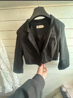 Svart bolero kavaj - Stilren svart croppad kavaj. Klassisk krage, 3/4 ärm Perfekt för en trendig och avslappnad look. Står L i men skulle säga att den passar S-M betydligt bättre