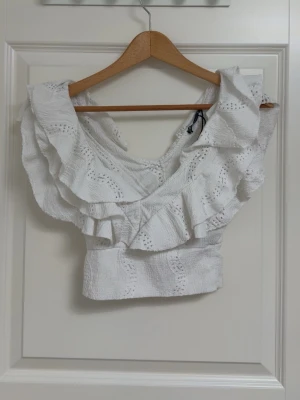 Vit volangblus med broderade detaljer - En vit croppad topp med breda volanger. 