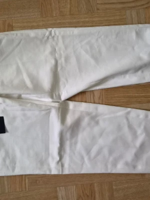 Vita byxor från STOCKH LM - Snygga vita linnebyxor från STOCKH LM i storlek 36. Byxorna har rak passform och är tillverkade i ett lätt och luftigt linnematerial, perfekta för en avslappnad och stilren look. Matcha med en enkel topp för en fräsch outfit.