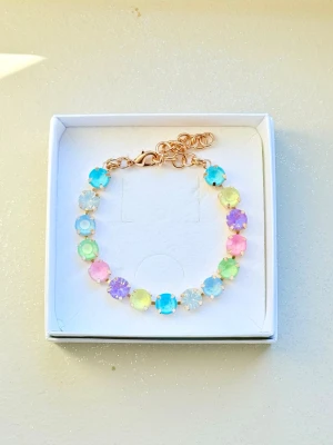 Pastellfärgat armband med stenar  - Armband med runda stenar 8 mm stora i pastellfärger som blått, grönt, rosa, lila och gult. Stenarna sitter i guldfärgad metall och armbandet har ett justerbart kedjelås. Perfekt för dig som gillar färgglada accessoarer och vill sticka ut lite extra. Bild 3 är en inspirationsbild för hur man kan kombinera det med andra smycken från tex Svedbom. Sista bilden är ett urval av färger som finns! 