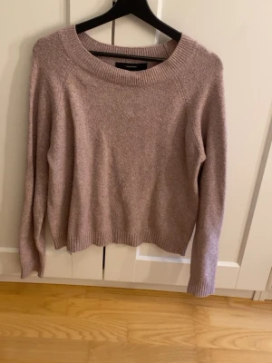 Ljusrosa stickad tröja  - Mysig ljusrosa stickad tröja från Vero Moda med rund halsringning och långa ärmar. Tröjan har en avslappnad passform och ribbstickade muddar vid ärmslut och nederkant. Perfekt för lager-på-lager och enkel att matcha med jeans eller kjol.