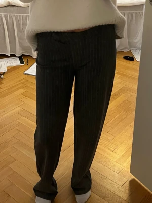 Grå kostymbyxor med kritstreck - Snygga grå kostymbyxor med smala vita kritstreck. Byxorna har rak passform och normal midja. Perfekta för en stilren look. Materialet känns mjukt och följsamt
