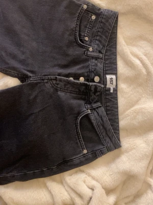 Svarta raka jeans från lager 157 - Snygga svarta jeans från lager 157 med raka ben och klassisk femficksmodell. Jeansen har låg midja och silverfärgade knappar. Perfekta för en avslappnad och trendig stil. Materialet är denim i bomull.