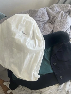 Svart helt ny kappa från Meotine - Snygg svart siden kappa från Meotine med krage, stora fickor framtill och knäppning med knappar. Jackan har en croppad passform och är fodrad med mörkgrönt tyg på insidan. Perfekt för dig som vill ha en stilren och trendig look. Kommer med päls och orginal påsen och är ej använd passar både small och medium 