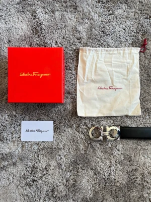Svart skärp från Salvatore Ferragamo - Säljer en nästan helt ny salvadore Ferragamo bälte som är använd några veckor. Det finns en liten repa på baksidan av loggan annars är det den mycket ny och bra ut.