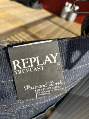 Mörkblå jeans från Replay Truecast - Snygga mörkblå jeans från Replay Truecast med klassisk femficksdesign och kontrastsömmar. Jeansen är tillverkade i denim och har en rak passform. Pure and Dark-modell, rinse washed utan kemiska behandlingar. W36 L 34