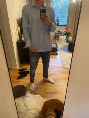 Ljusblå  hugo boss skjorta  - Snygg ljusblå skjorta med klassisk krage och knäppning framtill. Skjortan har lång ärm och en rak passform. Perfekt för en clean och stilren look. Passar till jeans eller chinos. Den är storlek 43 vilket jag skulle jämnförs med L. 