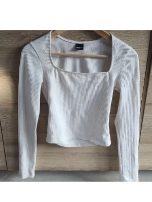 Vit ribbad topp från Gina Tricot - Säljer en vit ribbad långärmad topp från Gina Tricot med fyrkantig ringning. Toppen är figurnära och har en stilren design som passar perfekt till många olika outfits. Inga defekter, passar även storlek S!