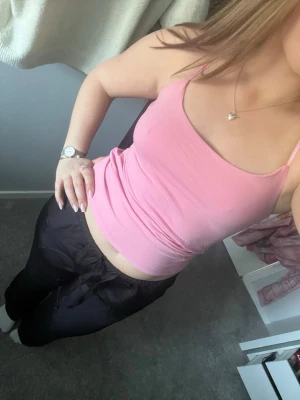 Rosa linne med smala axelband - Snygg rosa linne med smala axelband och figurnära passform. Perfekt att styla med jeans eller kjol för en fräsch look. Mjuk och stretchig känsla, passar dig som gillar enkla och stilrena plagg. Dubbeltyg vid bysten och justerbara band. Använd en gång.