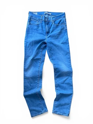Blå raka jeans från Levi's DAM - Snygga blå jeans från Levi's med klassisk femficksmodell och raka ben. Jeansen har normal midja och är gjorda i slitstark denim med tydliga sömmar. Perfekta för en avslappnad och trendig look. Dam