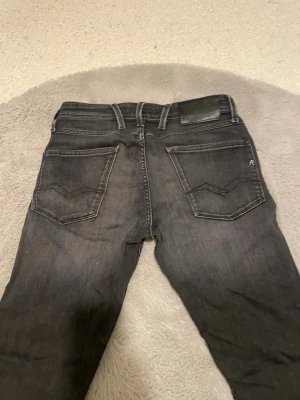 Svarta jeans från Replay Ambass - Snygga svarta jeans från Replay Ambass med klassisk 5 fickor samt med feta diskreta slitningar på baksidan. Längd 30 waist 27