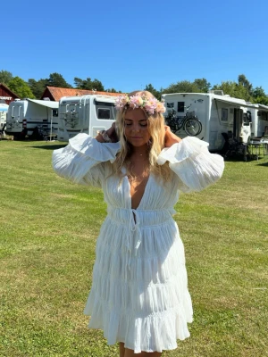 Vit klänning NAKD x Moa Mattsson - Säljer en vit kort klänning från Moa Mattssons kollektion med NAKD, den har djup v-ringning, knyt i midjan som är justerbar och volangdetaljer. Perfekt för sommaren och speciellt studenten / examen och midsommar!