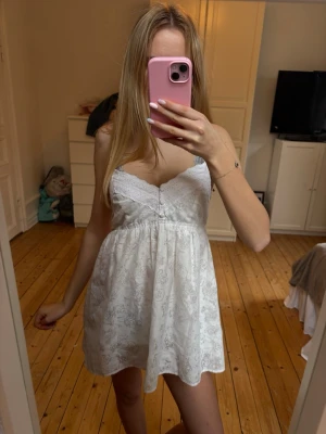 Vit klänning - Söt vit klänning med fina detaljer från Zoul i storlek 36. Fint skick, den är kort så var medveten om det💕