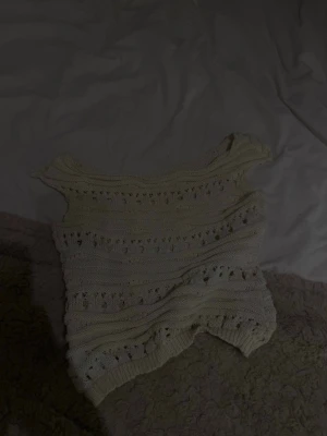  stickad ärmlös topp - Söt stickad topp med hålmönster och bred halsringning. Toppen är ärmlös och har en luftig känsla, perfekt för varmare dagar. Passar till både jeans och kjol för en avslappnad look.