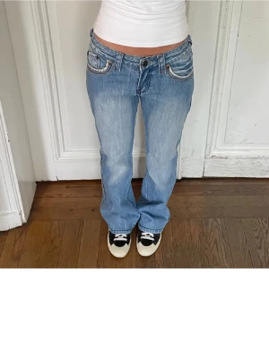 Ljusblå bootcut jeans - Säljer ett par ljusblå bootcut jeans med slitningar och snygga sömdetaljer vid fickorna. Köpt för 500 men alldrig andvänt! Storlek S, köpt på Plick. Bilden är från den jag köpte ifrån! 