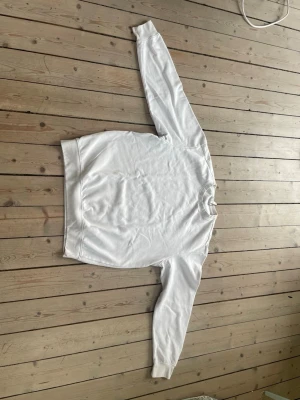 Vit H&M sweatshirt - Klassisk vit sweatshirt med rund hals och långa ärmar. Tröjan har ribbade muddar vid ärmslut och nederkant för en clean och avslappnad look. Perfekt att styla med jeans eller mjukisbyxor. Materialet känns mjukt och bekvämt mot huden.