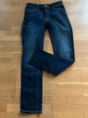 Mörkblå raka jeans från jack&jone - Säljer ett par mörkblå jeans från jack&jones med klassisk rak passform och kontrastsömmar. Jeansen har fem fickor, knappgylf och är tillverkade i kraftig denim. Perfekta för dig som gillar stilrena och tidlösa jeans.