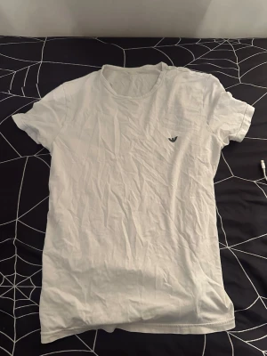 Vit t-shirt från Emporio Armani - Vit t-shirt från Emporio Armani med rund halsringning och liten logga på bröstet. Klassisk och enkel design som passar till det mesta. Tillverkad i mjuk bomull för en bekväm känsla.