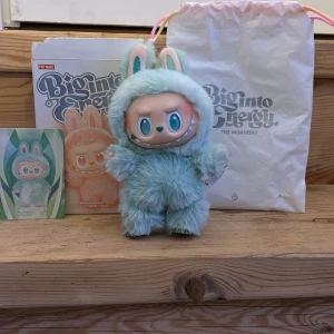 Labubu Serenity Edition - Söt samlarfigur från Pop Mart Big into Energy The Monsters, Serenity Edition. 100% äkta originalförpackning, samlarkort och tygpåse är med. Figuren är i nyskick perfekt för samlare eller som present.