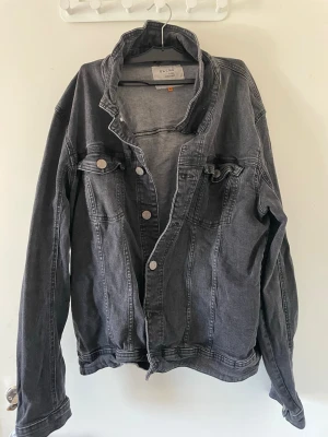 Svart jeansjacka från Blend XL - Snygg svart jeansjacka från Blend i storlek XL. Klassisk modell med knappar framtill, två bröstfickor med lock och knapp samt schyssta sömdetaljer. Perfekt oversized look och passar till det mesta. Materialet är slitstarkt jeans.