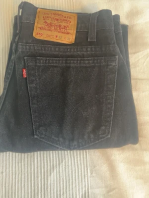 Levi's 550 svarta relaxed fit jeans - Säljer ett par svarta Levi's 550 jeans med relaxed fit och avsmalnande ben. Klassisk femficksmodell med Levi's röda etikett på bakfickan och ikonisk läderpatch i midjan. Tillverkade i slitstark denim, perfekta för en avslappnad och stilren look.