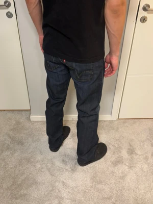 Levis 506 Standard - Mörlblå Levis 506 Standard i riktigt fint skick, inga defekter. Modellen på bilderna är 183cm och väger 67kg. Mått: Midja: 40cm, Lår: 28cm, Benslut: 21cm, Ytterben: 106cm. Skriv vid funderingar!   