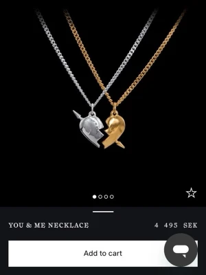 You & Me halsband i guld och silver - Två halsband med hjärthängen i guld- och silverfärg som tillsammans bildar ett brutet hjärta. Ena halvan har en pil genom sig och ett ansikte i profil. Kedjorna är i matchande färger och har en modern, stilren design. Båda är nästan i nytt skick, är öppen för prisförslag 