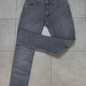 Grå slim fit jeans från Jack and jones - Snygga grå slim fit jeans från Jack and Jones  med klassisk femficksdesign och diskret logga på bakfickan. Jeansen har normal midja och är tillverkade i stretchigt denim för en bekväm passform. Perfekta för en stilren och avslappnad stil.