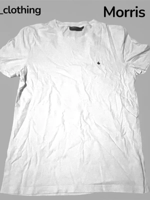 Vit t-shirt från Morris - Vit t-shirt från Morris med liten broderad logga på bröstet. Klassisk passform och rund halsringning, tillverkad i mjuk bomull. Perfekt basic-plagg för en clean och stilren look.