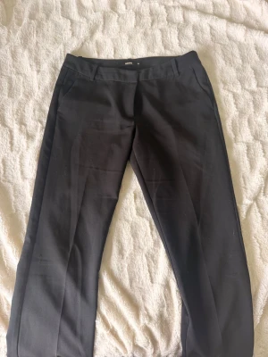 Svarta lågmidjade kostymbyxor från Bik Bok💗 - Klassiska svarta kostymbyxor från Bik Bok med raka ben och pressveck. Perfekta för en stilren och clean look. Materialet känns mjukt och följsamt. Byxorna är lågmidjade och i storlek 38 ☺️De är även ganska använda så därmed är de lite noppriga längs benen men inget som syns mycket 💕 Kan skicka fler bilder om så önskas 😇