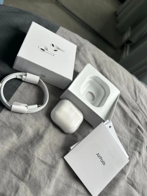 Apple AirPods Pro med laddningsetui - Säljer ett par vita Apple AirPods Pro med trådlöst laddningsetui. Hörlurarna är i klassisk Apple-design, kompakta och smidiga med silikonproppar. Medföljer originalkartong, laddkabel och manualer. Perfekta för musik, samtal och träning.