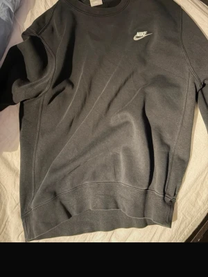 Svart sweatshirt från Nike - Snygg svart sweatshirt från Nike med klassisk logga på bröstet. Tröjan har rund halsringning, långa ärmar och ribbade muddar vid ärmslut och nederkant. Perfekt för en avslappnad och sportig stil.