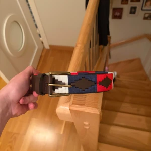 Röd-blå-vitt broderat bälte - Helt nya skärp för endast 349 kr, de är 1 one size. Handgjorda med mjukt högkvalitets läder med brodering i mörk blå och ljud blå färg ett hål i bältet märks knappt av! Annars väldigt bra skick!. Gör så att din outfit sticker ut mer med Nordfors bälten!y