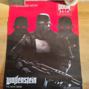 Wolfenstein: The New Order affisch - Stor affisch för spelet Wolfenstein: The New Order med svart bakgrund och röda detaljer. Motivet visar tre soldater i futuristiska hjälmar och rustningar, med ett stort vapen i förgrunden.   Måttet på affischen är 50x70 cm.  Finns en del märken men inget som stör själva motivet i fråga.