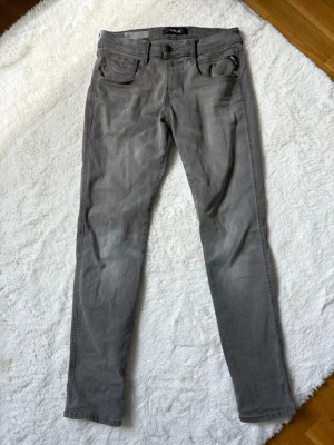 Gråa jeans från Replay - Säljer ett par gråa jeans från Replay med klassisk femficksdesign och dragkedja. Jeansen har en smal passform och är tillverkade i stretchigt material för extra komfort. 