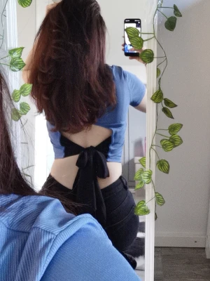 Blå ribbad croppad topp med knyt - Trendig blå croppad topp med ribbad struktur och korta ärmar. Toppen har öppen rygg med en stor knytning baktill som ger en snygg detalj. Perfekt för dig som vill ha en unik och stilren look.