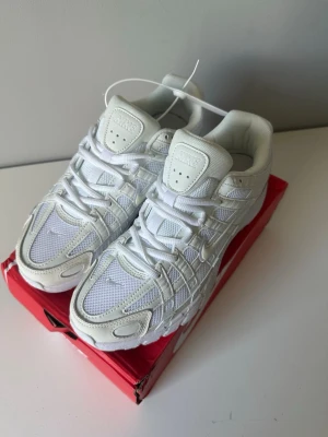 Nike vita sneakers p6000 - Nike P6000 i helvitt med mesh och syntetiska paneler. Snygg sportig design med tydliga detaljer och broderad Swoosh på sidan. Skorna har tjock sula och klassisk snörning. Perfekta för dig som gillar stilrena och fräscha sneakers.