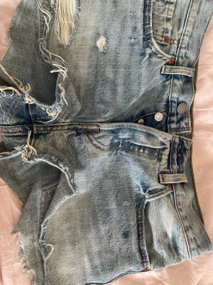 Levi's ljusblå jeansshorts med slitningar - Blå jeansshorts från Levi’s i bra skick. De har två små fläckar, se sista bilden. Storlek S-M. Kommer inte till användning