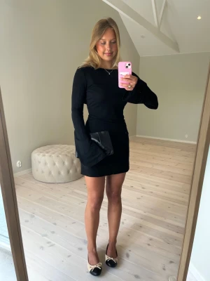 Svart långärmad kortklänning - Stilren svart kortklänning med långa ärmar och rund halsringning. Klänningen har en figurnära passform och är perfekt för dig som gillar en enkel men snygg look. Materialet känns mjukt och stretchigt, vilket gör den bekväm att bära hela dagen.